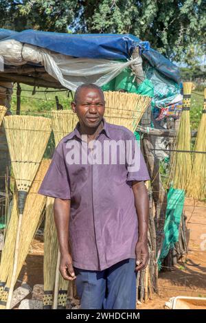 african old entrepreneur man making brooms, street vendor with a small stall at the side of the highway Stock Photo