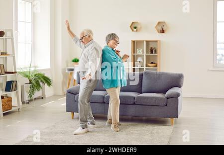 Happy cheerful married senior couple having fun and dancing in living room at home Stock Photo