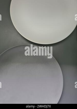 a white and a gray plate on a gray background on the theme of contrasts and minimalism Stock Photo