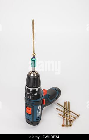 Cordless drill driver with bit holder and inserted Torx bit, Torx wood screw, white background, Stock Photo