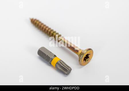 Single Torx chipboard screw with countersunk head, yellow galvanized, Torx bit, blurred, white background, Stock Photo