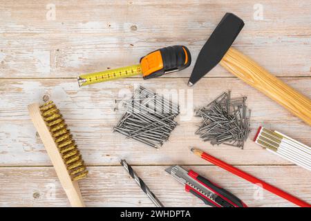 Locksmith's hammer 1000 g, steel nails, folding rule, carpenter's pencil, cutter knife, wood drill, brass hand wire brush, tape measure, wood background, Stock Photo