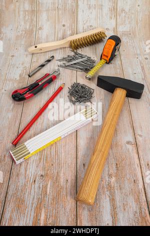 Locksmith's hammer 1000 g, steel nails, folding rule, carpenter's pencil, cutter knife, wood drill, brass hand wire brush, tape measure, wood background, Stock Photo