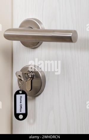 Key with black key fob inserted in the door lock, labeled 'Home Office', Stock Photo