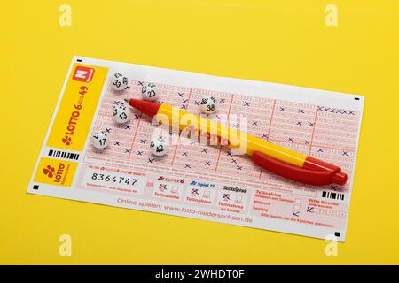 Lotto balls lying on completed lottery ticket, LOTTO 6aus49, lotto ballpoint pen, yellow background, Stock Photo