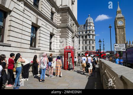 Tourists queuing to take a photo with the iconic K2 red phone box, with Big Ben in the background Parliament Square, London, UK.  9 Aug 2023 Stock Photo