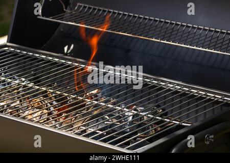 Barbecue grill pit with glowing and flaming hot open fire with red flame, hot charcoal briquettes and embers Stock Photo