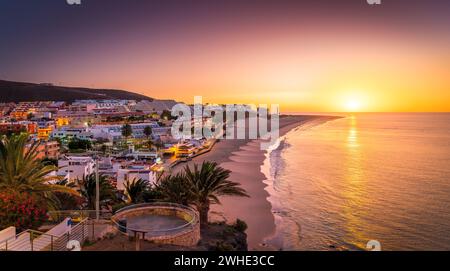 Bask in the warm glow of sunset at Morro Jable, Fuerteventura, where golden sands meet tranquil Atlantic waters—a photographer dream Stock Photo