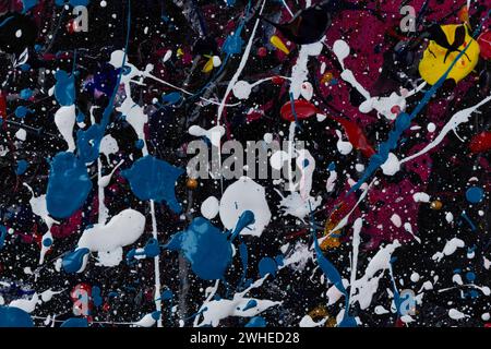 Macro close-up of an abstract, messy and colorful acrylic paints on black canvas background. Splashes, blobs, drips, stains and spray. Stock Photo
