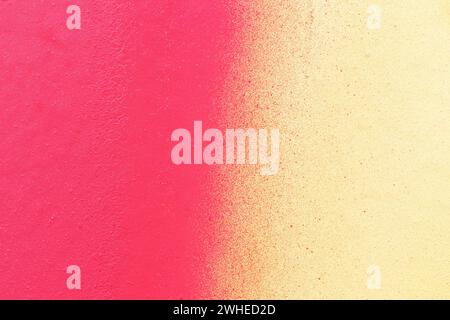 Macro close-up of a wall spray painted with pink and yellow. Abstract full frame textured splattered graffiti background with copy space. Stock Photo