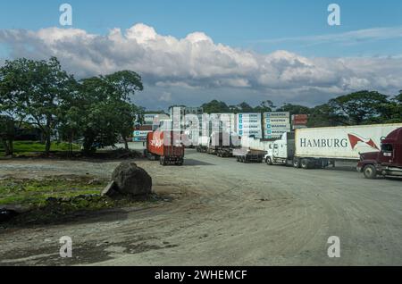 Costa Rica, San Juan Grande - July 22, 2023: Shipping container storage field along highway 27. Stacks of them and trucks coming in under blue cloudsc Stock Photo