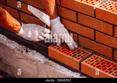 Builder laying bricks on construction site. Stock Photo