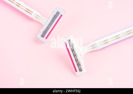 Two plastic, disposable razors on pink color background. Stock Photo
