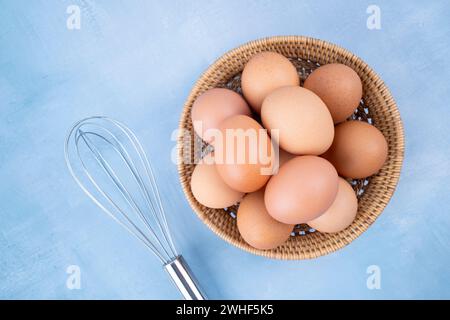 Top view of organic chicken eggs in basket on blue wooden background. Stock Photo