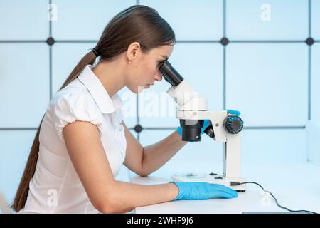 Woman looking through microscope Stock Photo