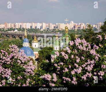 Orthodox cross on a background of the sky and the city in purple flowered garden Stock Photo