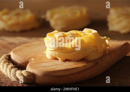 Raw italian pasta tagliatelle on wooden cutting board Stock Photo