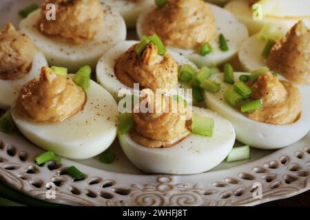 Deviled eggs with cod livers with leek on white plate. Rustic wooden table Stock Photo