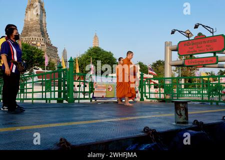 Two Thai Buddhist monks standing on the pier by (temple) Wat Arun next to the Chao Phraya River in Bangkok, Thailand, waiting to catch a boat Stock Photo