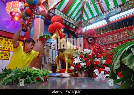 At Sanjao Kuan Teh (Kuan Teh Old Temple) in Chinatown, Bangkok, Thailand, a temple employee feeds greens to a statue of famed Chinese war horse Chi Tu Stock Photo