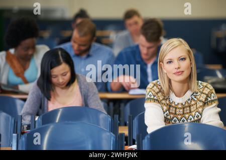 University, students and portrait in course lecture and learning in classroom for education. College, campus and people studying for test in academy Stock Photo