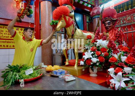 At Sanjao Kuan Teh (Kuan Teh Old Temple) in Chinatown, Bangkok, Thailand, a temple employee feeds greens to a statue of famed Chinese war horse Chi Tu Stock Photo