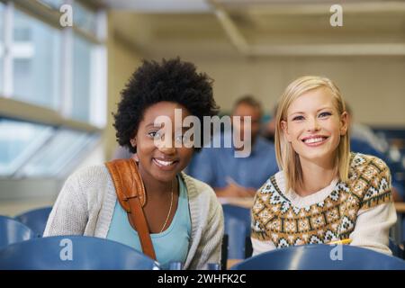 Portrait, college and women students in classroom with positive, good and confident attitude. Smile, happy and young female friends with scholarship Stock Photo