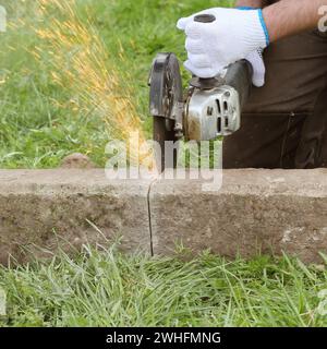 Construction worker cutting concrete plate for fence foundation using a ...