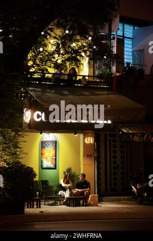 Ho Chi Minh City, Vietnam - February 2, 2024: Two couples on a date in a street cafe at night. Young Asian people sitting and talking in a coffeeshop Stock Photo