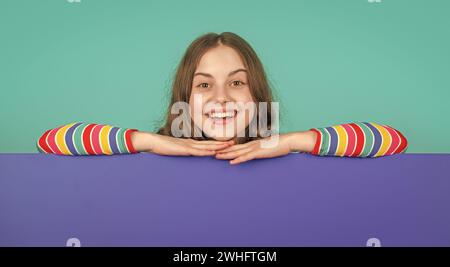 laughing child behind blank blue paper with copy space for advertisement Stock Photo