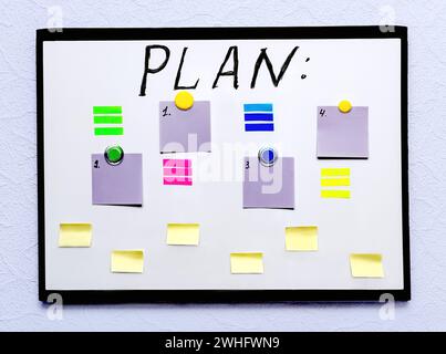 White board with a plan and colored sheets of paper for notes, on a light wall Stock Photo