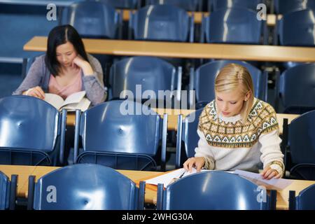 University, students and writing notes in lecture, hall and learning in class with education. College, campus and people studying for test in school Stock Photo