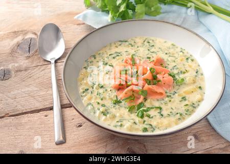 Homemade vegetarian cream soup from parsley leaves and potatoes with strips of smoked salmon on a rustic wooden table, copy spac Stock Photo