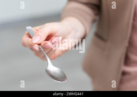 Metallic empty eating spoon in a human right hand with clipping path isolated on white Stock Photo