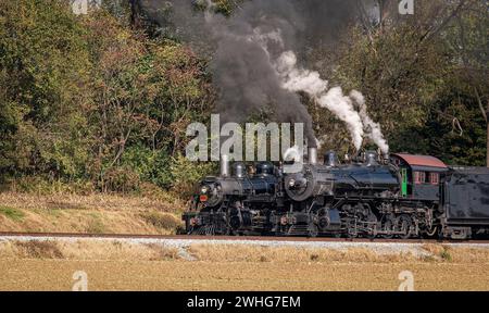 View of Two Steam Engines, blowing Smoke and Steam Warming Up Next to Each Other on a Sunny Day Stock Photo