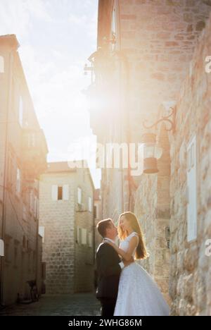 Groom lifted bride by the waist near the old stone house Stock Photo