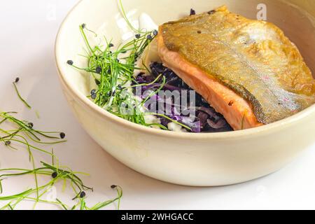 Char fish filet roasted on the skin with red cabbage kimchi, cream sauce and sprouts served in a bowl, selected focus, Stock Photo