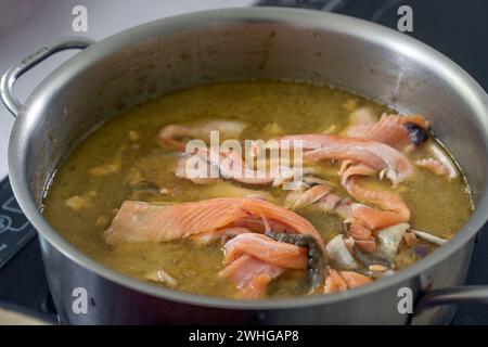 Base for a fish soup or sauce with carcasses, trimmings and skin cuttings is boiled down in vegetable broth and wine a large pot Stock Photo