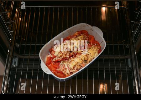 Casserole with baked bell peppers with rice, tuna, tomatoes and cheese on a grid in the oven, copy space Stock Photo