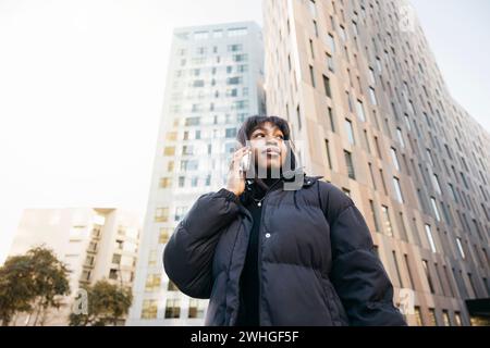 Young beautiful black woman wearing black clothes talking on a phone while walking on a city. Stock Photo