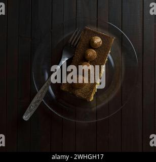 Truffle cake on glass plate on dark wooden table. Stock Photo
