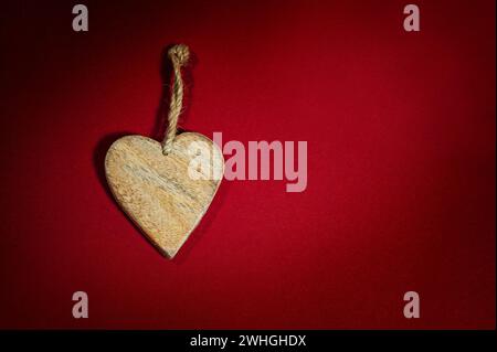 Simple heart shape made of wood with a rustic cord on a background of dark red felt, holiday greeting card and love symbol for v Stock Photo