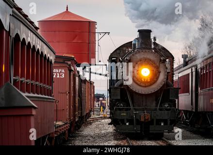 View of a Classic Steam Passenger Train Arriving into a Train Station Blowing Smoke and Steam Stock Photo