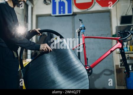 Mechanic repairman assembling wheel custom bicycle in workshop. Stock Photo