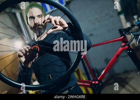 Mechanic repairman assembling wheel custom bicycle in workshop. Stock Photo