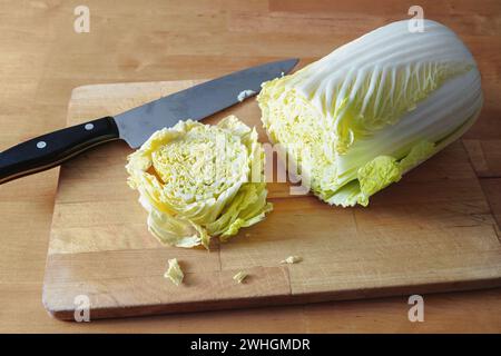 Cut slice of raw Chinese or napa cabbage on a wooden board and a kitchen knife, vegetarian cooking with vegetables, copy space, Stock Photo