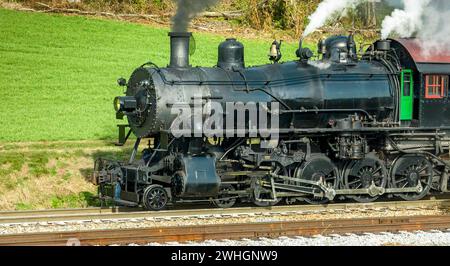 Close Side Aerial View of a Steam Engine Waiting, all Steamed Up, While it is Blowing Smoke Stock Photo