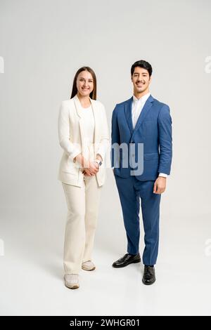 Two professionals in a business environment, a woman in a cream suit and a man in a blue suit, stand confidently, reflecting a successful business duo ready for collaboration and leadership. Stock Photo