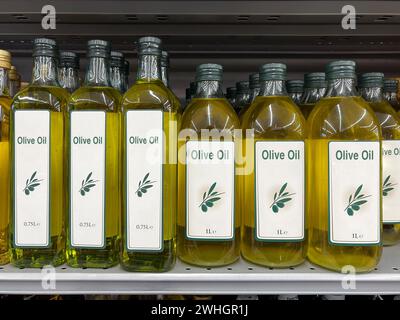 Olive oil in one-liter and 750-ml glass bottles on the shelf Stock Photo