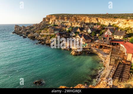 Il-Mellieha, Malta - Panoramic skyline view of the famous Popeye Village at Anchor Bay at sunset Stock Photo